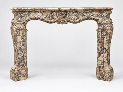 un encadrement de cheminée ancien en marbre, orné d'un motif sculpté