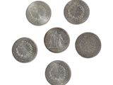 six pièces d'argent sont disposées en cercle sur une surface blanche
