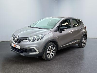 Une voiture grise est garée dans une pièce au sol noir.