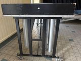 a metal table with a black top and silver pipes on it
