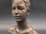 bronze sculpture of a woman ' s head on a gray background