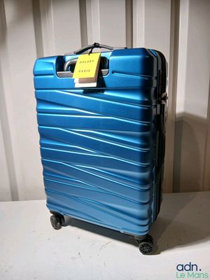 une valise bleue avec une étiquette, posée sur une table