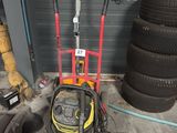 a yellow and red hand truck with a tire in the garage