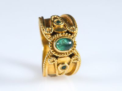une image d'un gros plan d'une bague en or avec une pierre verte