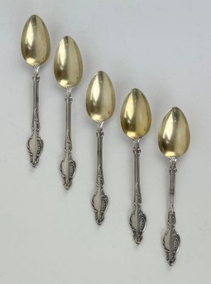 six silver spoons are lined up in a row on a white surface