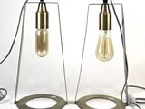 two light bulbs are sitting on a metal stand with a wire