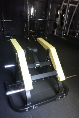 des appareils de musculation jaunes et noirs dans une salle de sport au sol noir