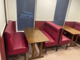 tables and benches in a room with red booths and windows