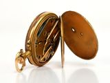 a close up of a pocket watch on a white surface