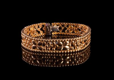 gros plan d'un bracelet en or sur une surface noire
