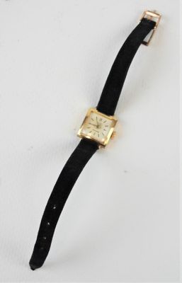 une photo d'une montre en or avec un bracelet en cuir noir