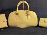 un sac à main jaune et un portefeuille posés sur un fond noir