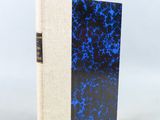 un livre à la couverture bleue et noire posé sur une table blanche