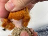 a person that is holding a small doll in their hand