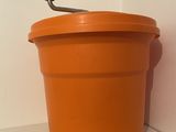 an orange bucket with a handle sitting on a shelf