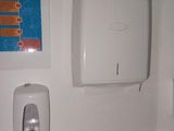 a toilet with a paper towel dispenser on the wall