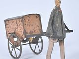 une figurine représentant un homme avec une charrette sur fond blanc