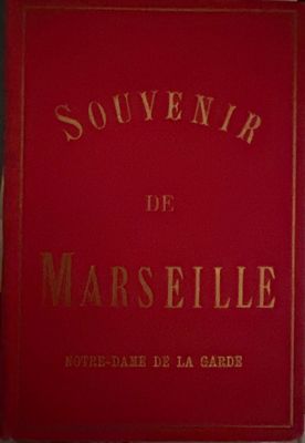 an old red book with gold lettering sitting on top of a table