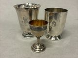 deux tasses en argent et une tasse en argent posées sur une surface blanche