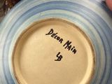a person holding a blue and white plate with a name on it