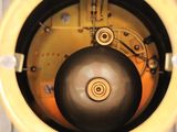 a close up of a yellow clock with a black ball in it