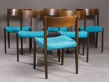 four chairs with blue upholstered seats sit in front of a gray wall