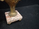 a gold vase with flowers in it on a black surface