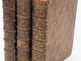 three old books sitting on top of each other on a white surface