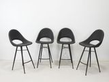 trois chaises noires empilées les unes sur les autres devant un mur blanc