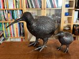 une statue représentant deux oiseaux, posée sur une table devant une bibliothèque