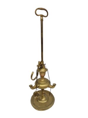une lampe à huile ancienne en laiton, posée sur un support muni d'une poignée