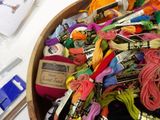 a wooden bowl filled with different colored threads and scissors