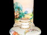 a white vase with a painting on it sitting on a table