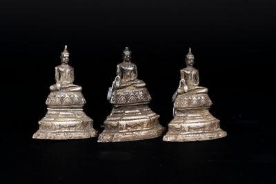 three silver figurines of buddhas sitting on top of a table