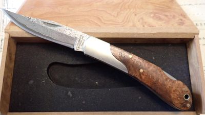 un couteau dans une boîte en bois posée sur une table