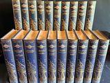 douze livres à la couverture bleue rehaussée de dorures, posés sur un fond noir