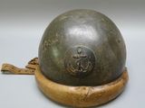 a metal helmet on a wooden stand on a white surface