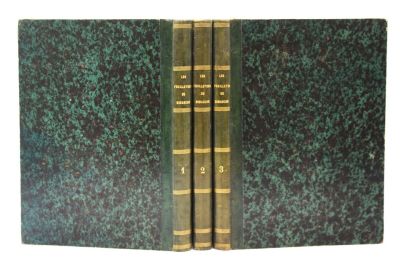trois livres sont empilés sur une surface blanche