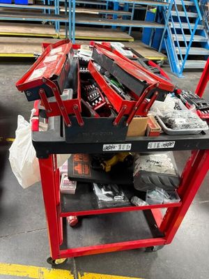 un établi rouge sur lequel sont posés des outils, dans un entrepôt