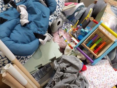 a baby in a stroller next to a pile of toys