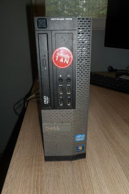 un ordinateur posé sur un bureau, avec un ventilateur dessus
