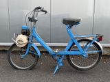 une photo d'un vélo bleu garé devant un immeuble