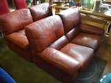 a brown leather couch sitting in a room with other furniture in the background