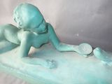 a statue of a baby laying on a bed with a tennis racket