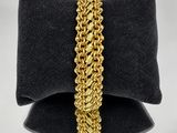 un gros plan d'un bracelet à maillons dorés posé sur un coussin noir