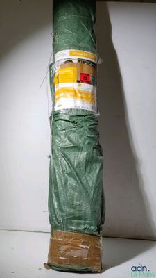 a large green umbrella wrapped in plastic on a shelf