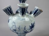 a blue and white vase with four cups on it