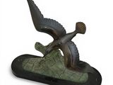 statue of a bird flying over a log on a white background