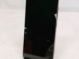 a black cell phone sitting on a stand on a white surface