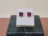a pair of pink sapphire earrings sitting on top of a marble block